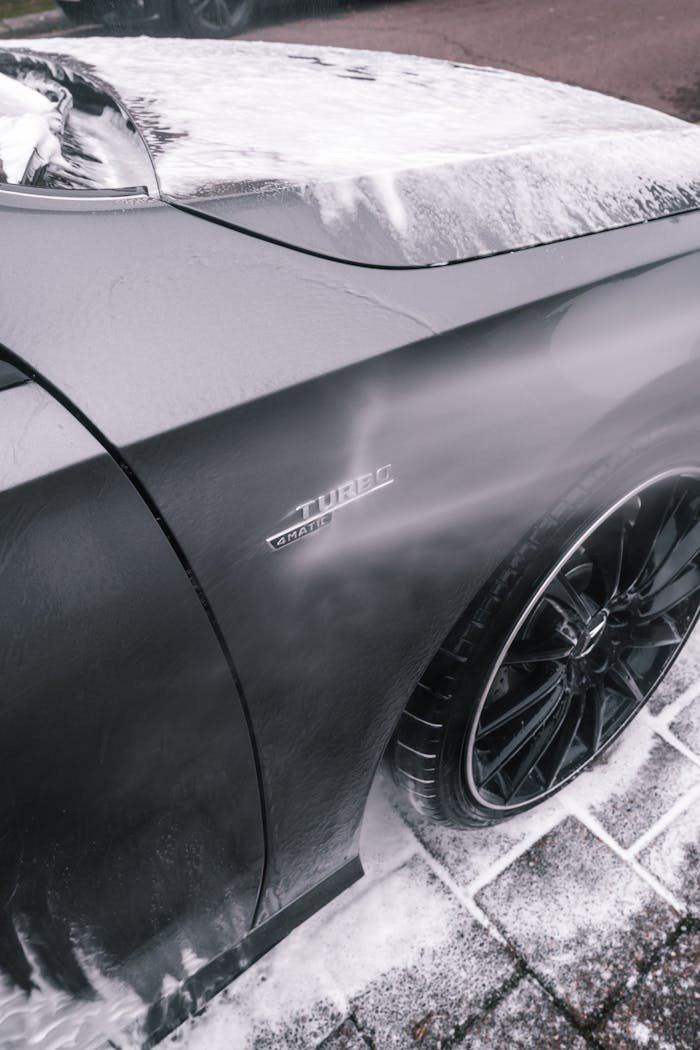 menu-01 Close-up of a sleek black car being washed with foam, highlighting its shiny surface and modern design.